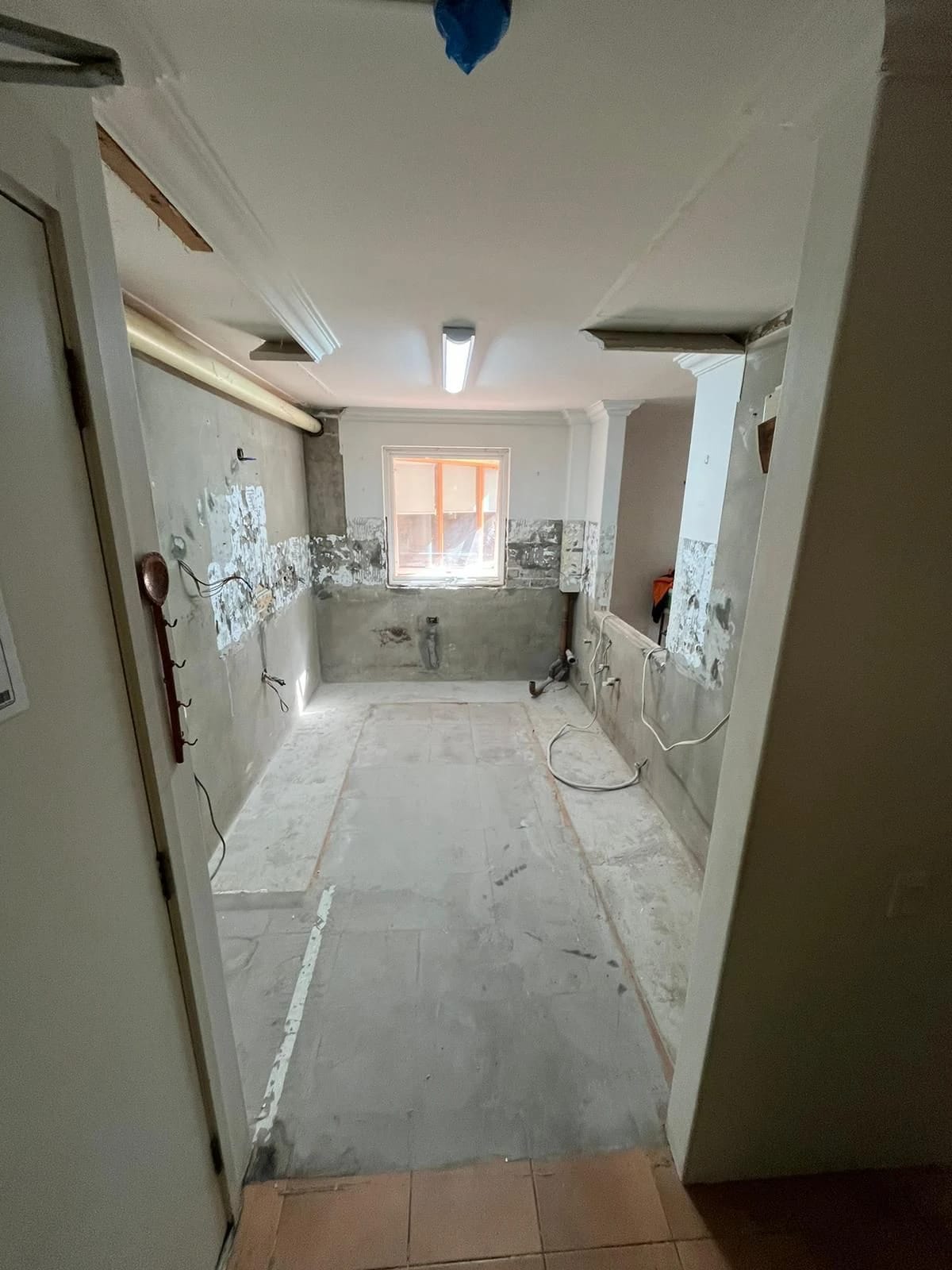 Same galley kitchen after cabinets, appliances and floor finishes were removed