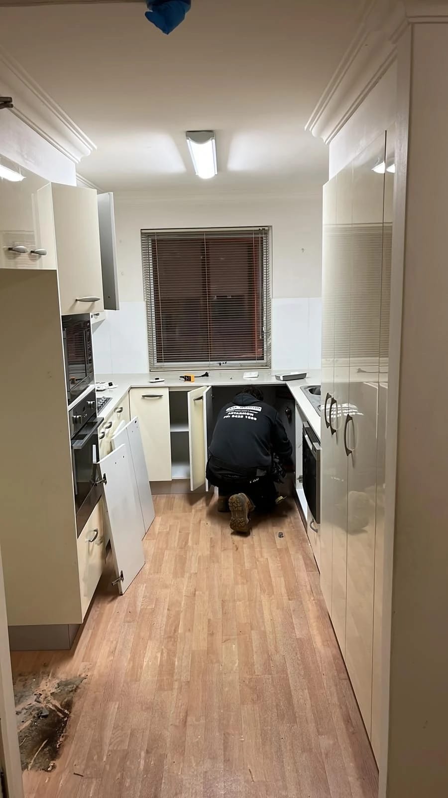 Compact galley kitchen with cabinets, appliances and timber-look flooring before strip out
