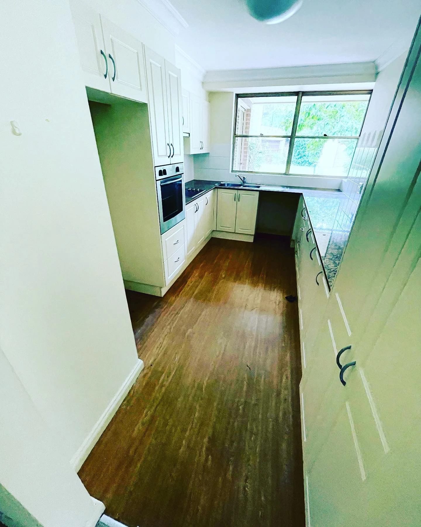 Green galley kitchen with cabinetry, appliances and timber flooring before strip out