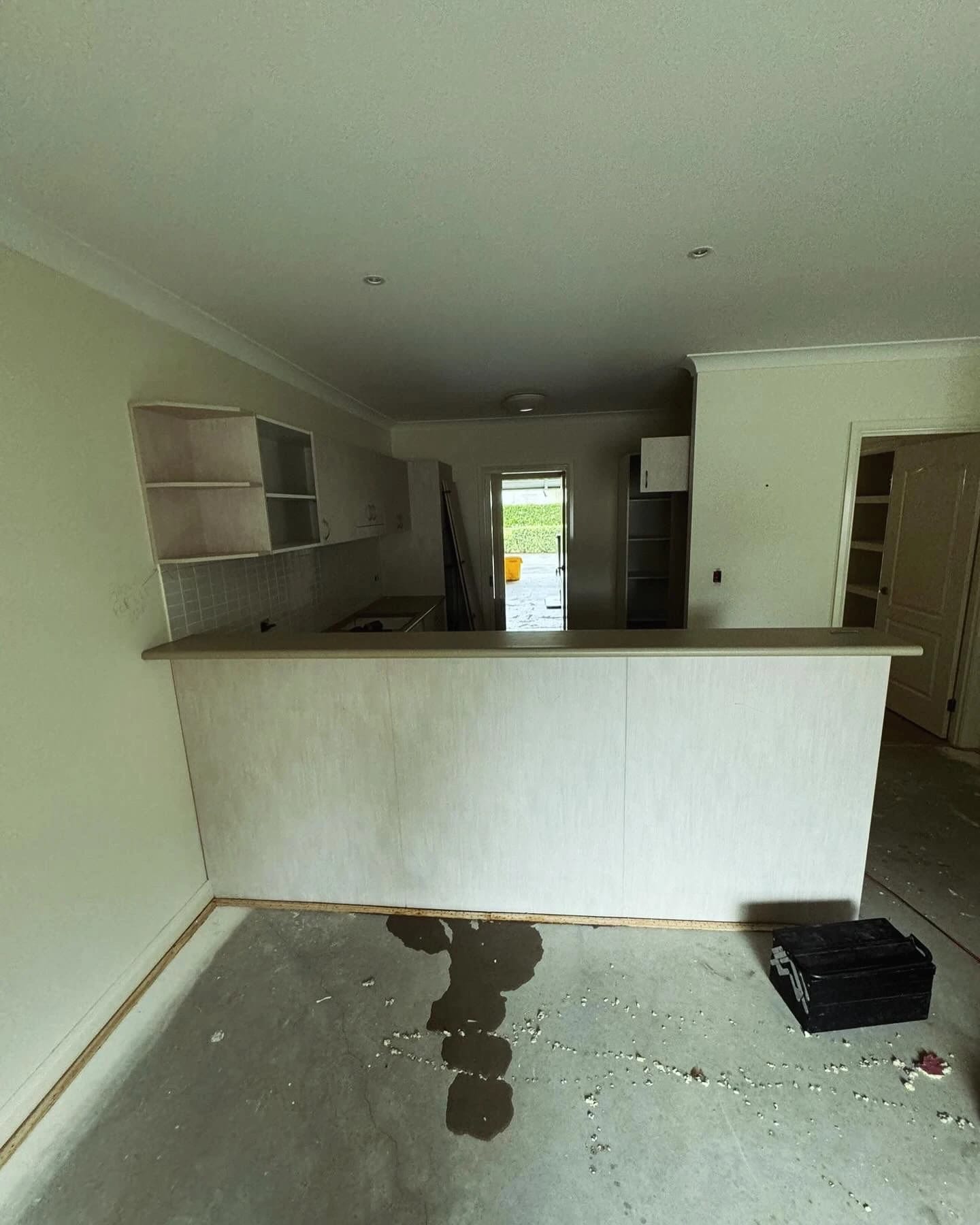 Open-plan kitchen with cabinetry and breakfast bar before strip out
