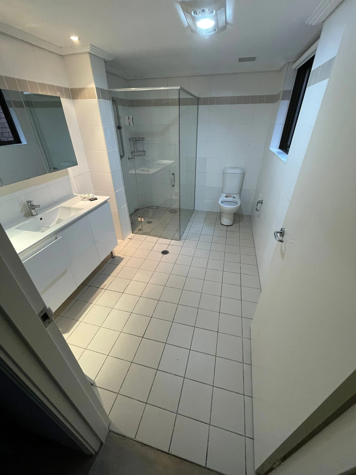 Tiled bathroom with vanity, shower screen and toilet before strip out