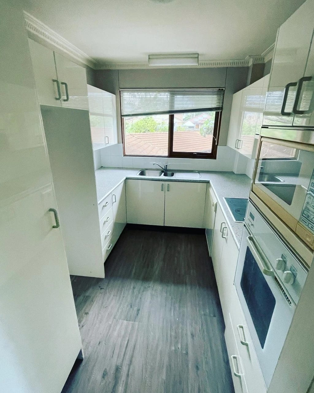 White fitted kitchen with appliances and flooring before strip out