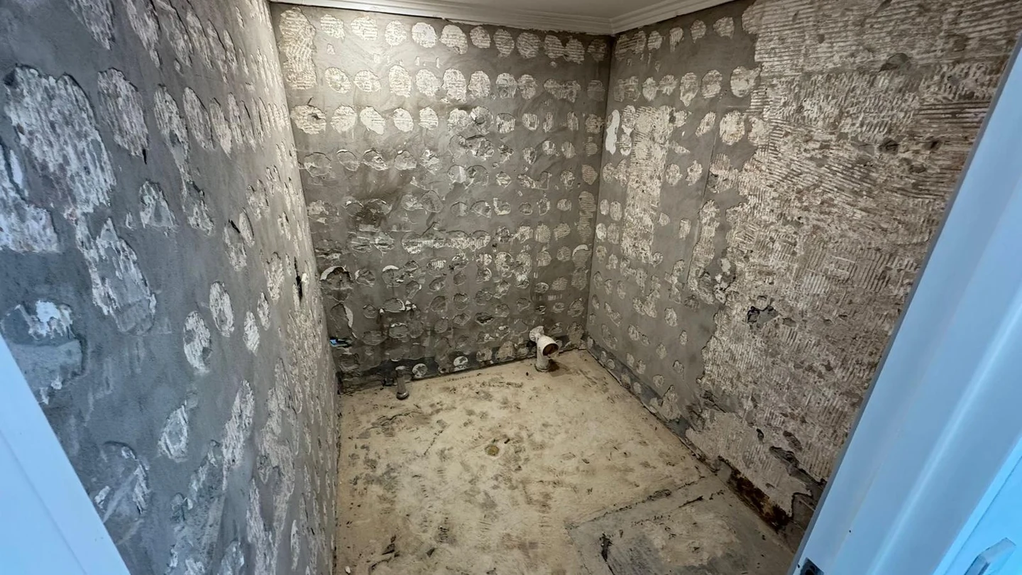 Second view of the stripped bathroom with masonry walls and service points exposed