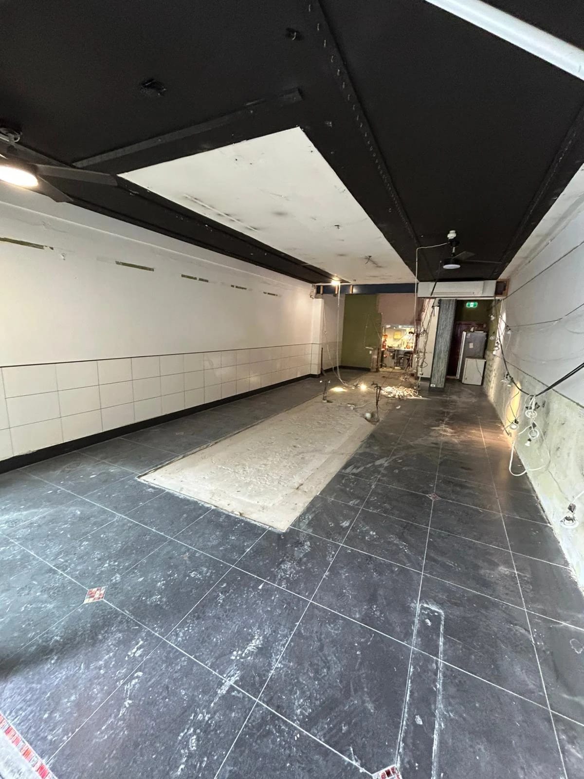Cleared retail tenancy with low wall tiles, ceiling and lighting retained