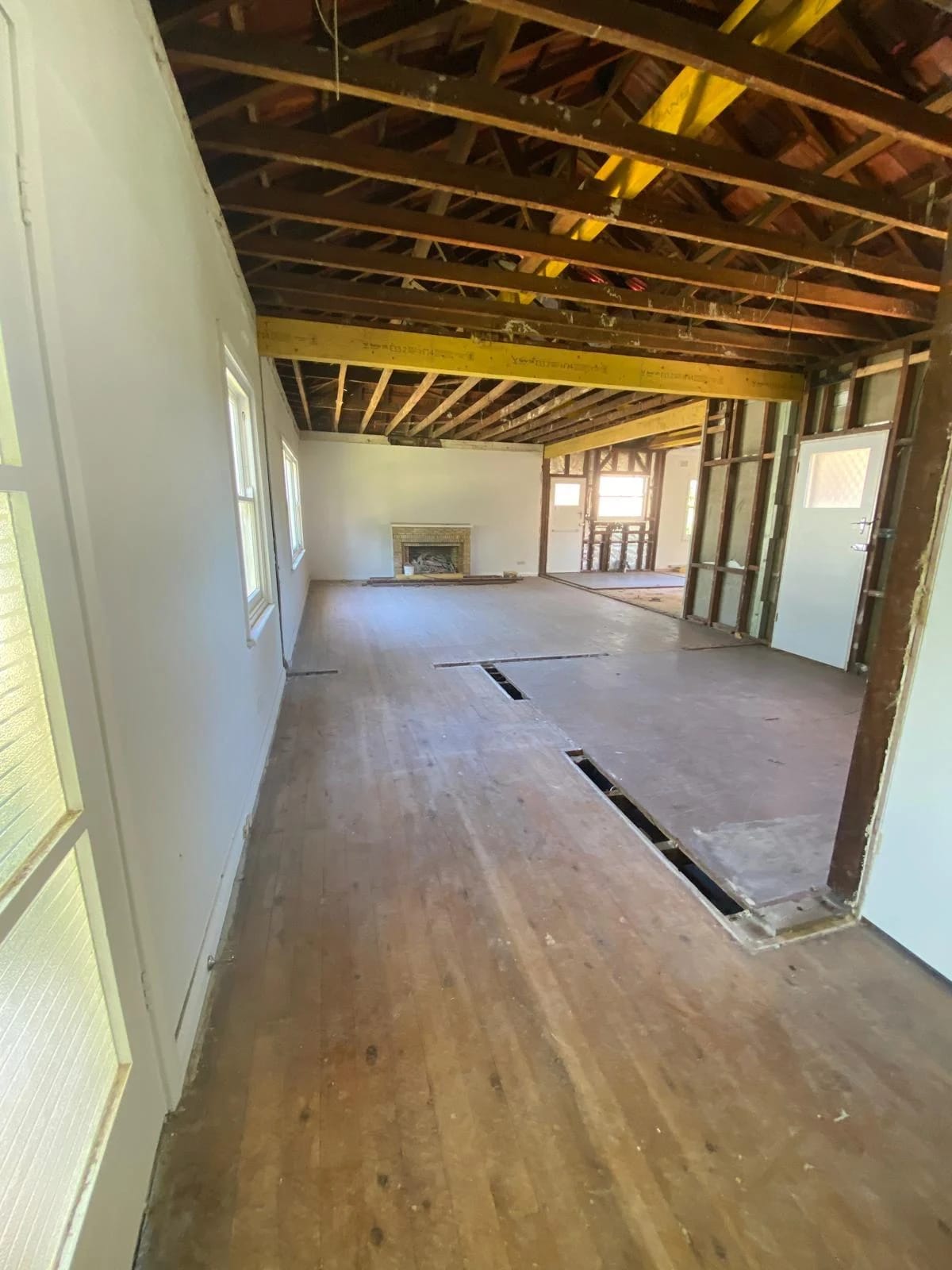 Long open-plan view after partition removal with timber floors retained