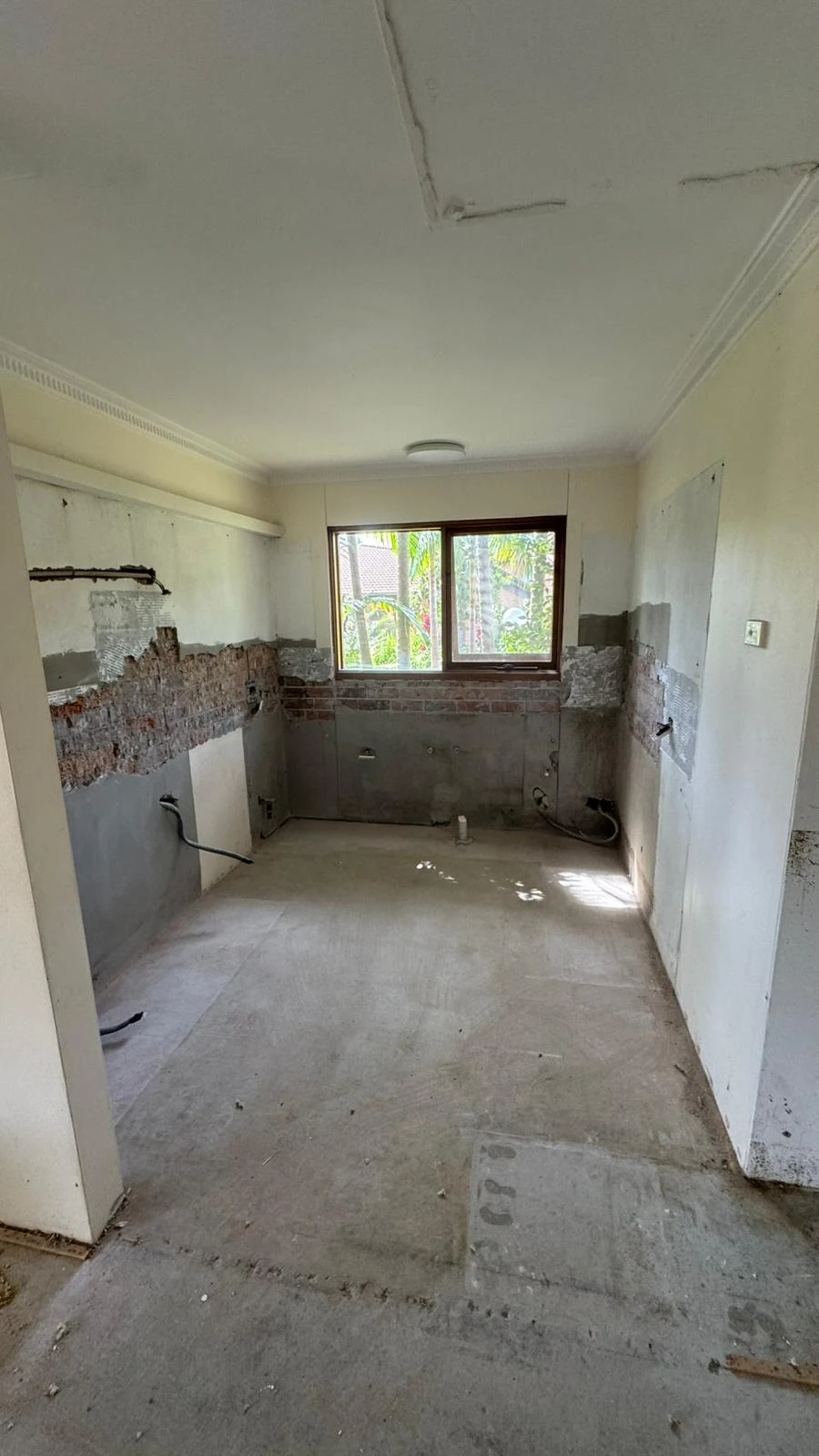 Compact corner kitchen after cabinetry, appliances and wall finishes were removed