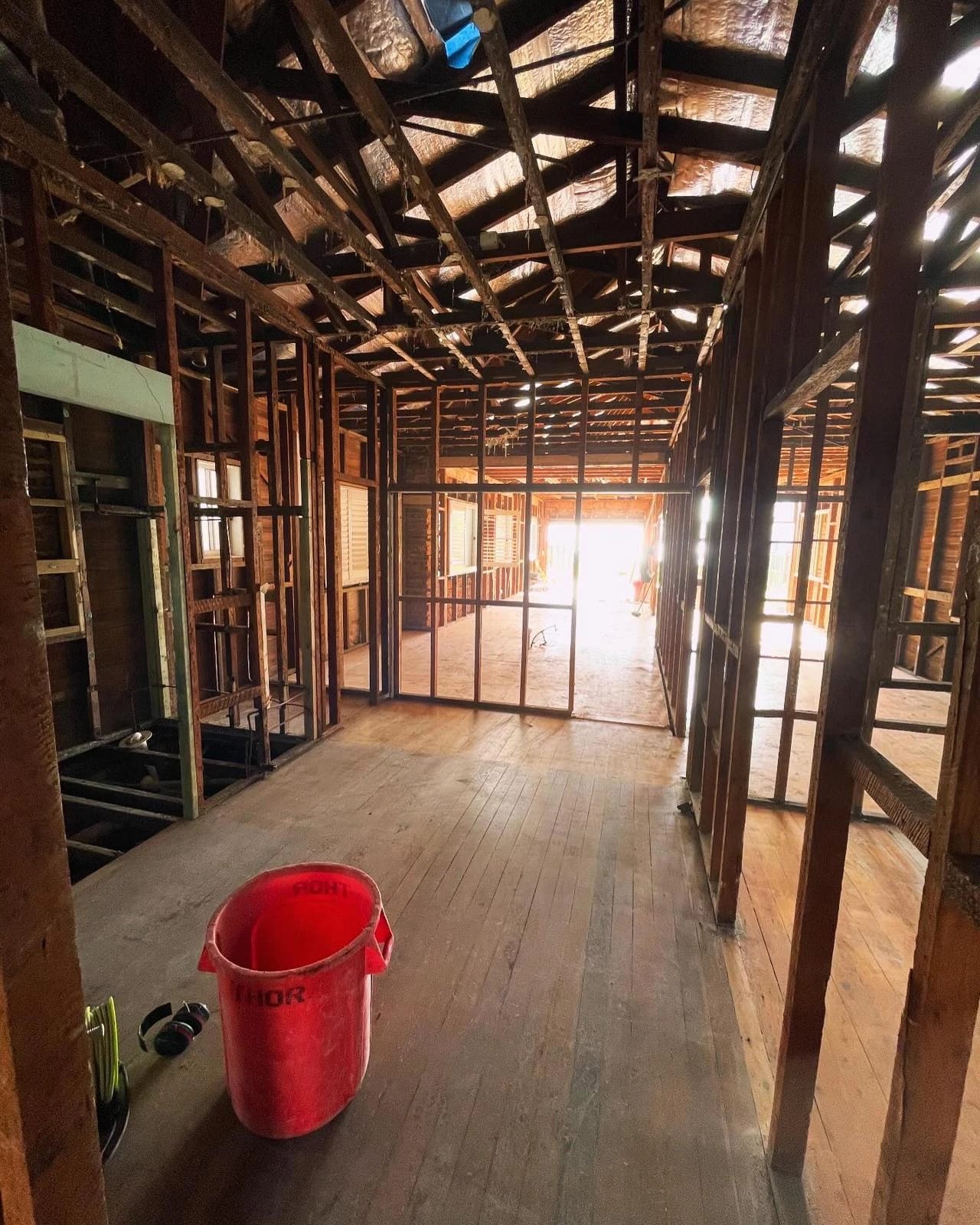 Residential interior stripped back to timber wall and roof framing with floorboards retained