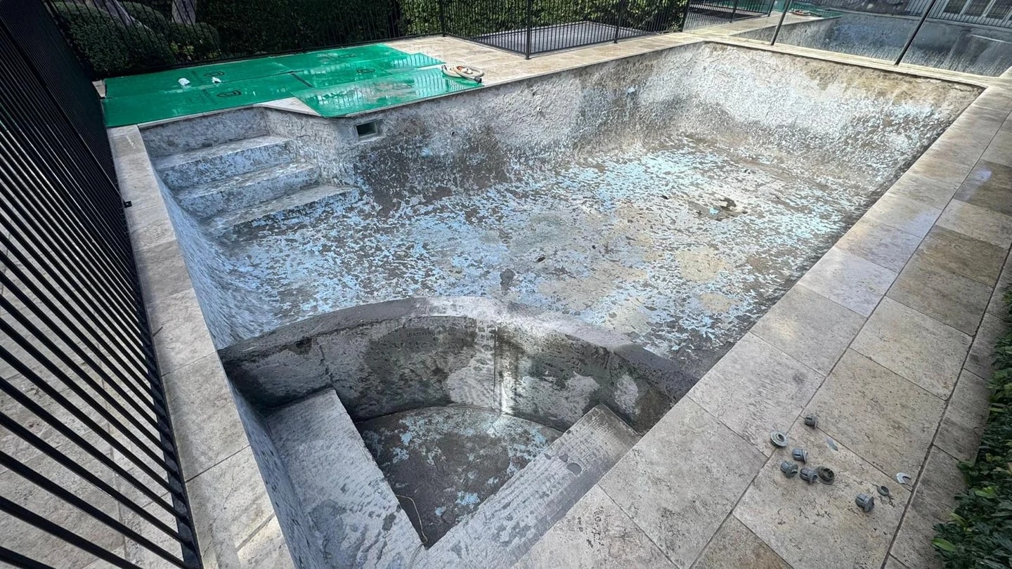 Compact residential pool with blue interior tiles stripped to the substrate