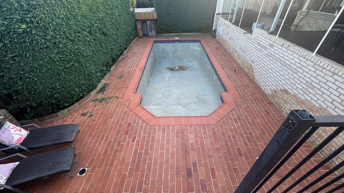 Residential pool before strip out with brick paving around the shell