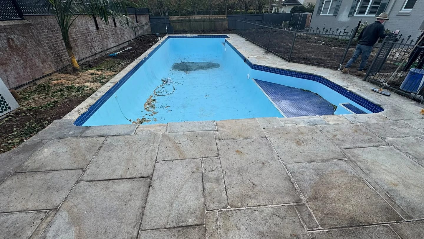 Long view of the drained residential pool before the blue interior surface was removed