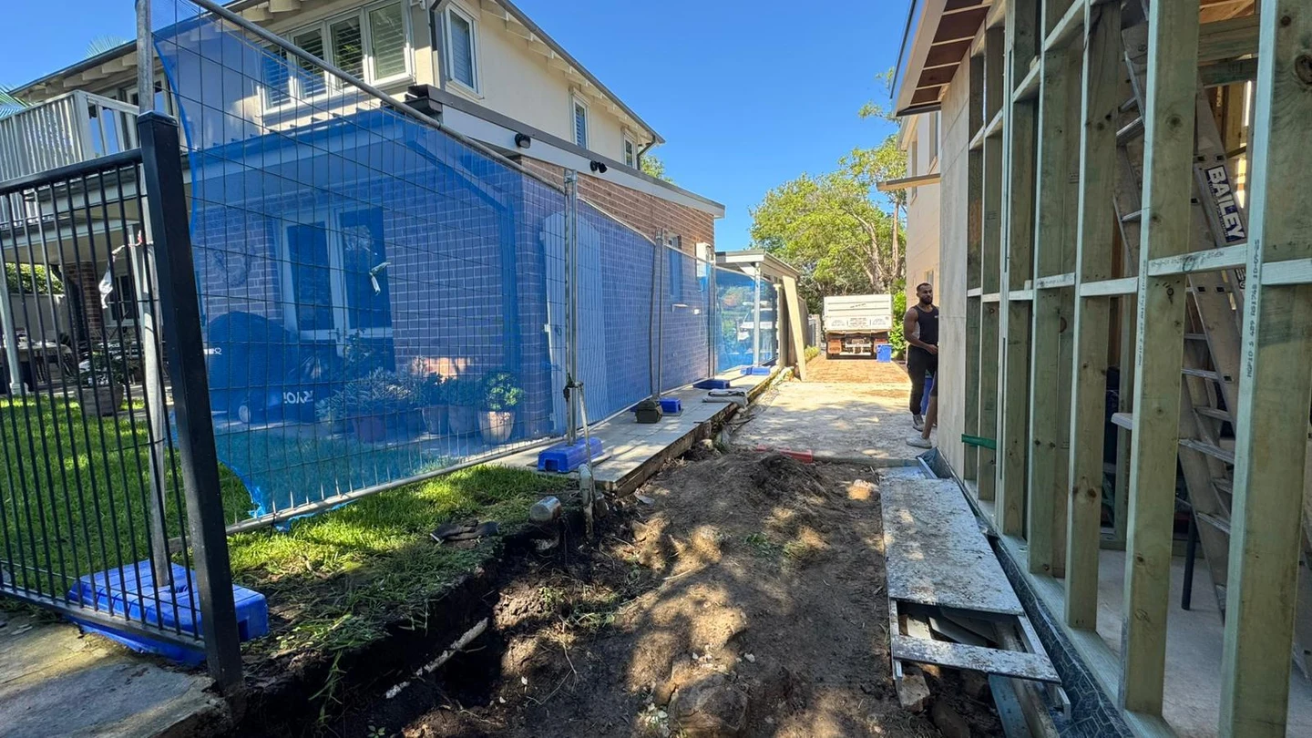 Open residential side yard with exposed ground beside retained boundary fencing