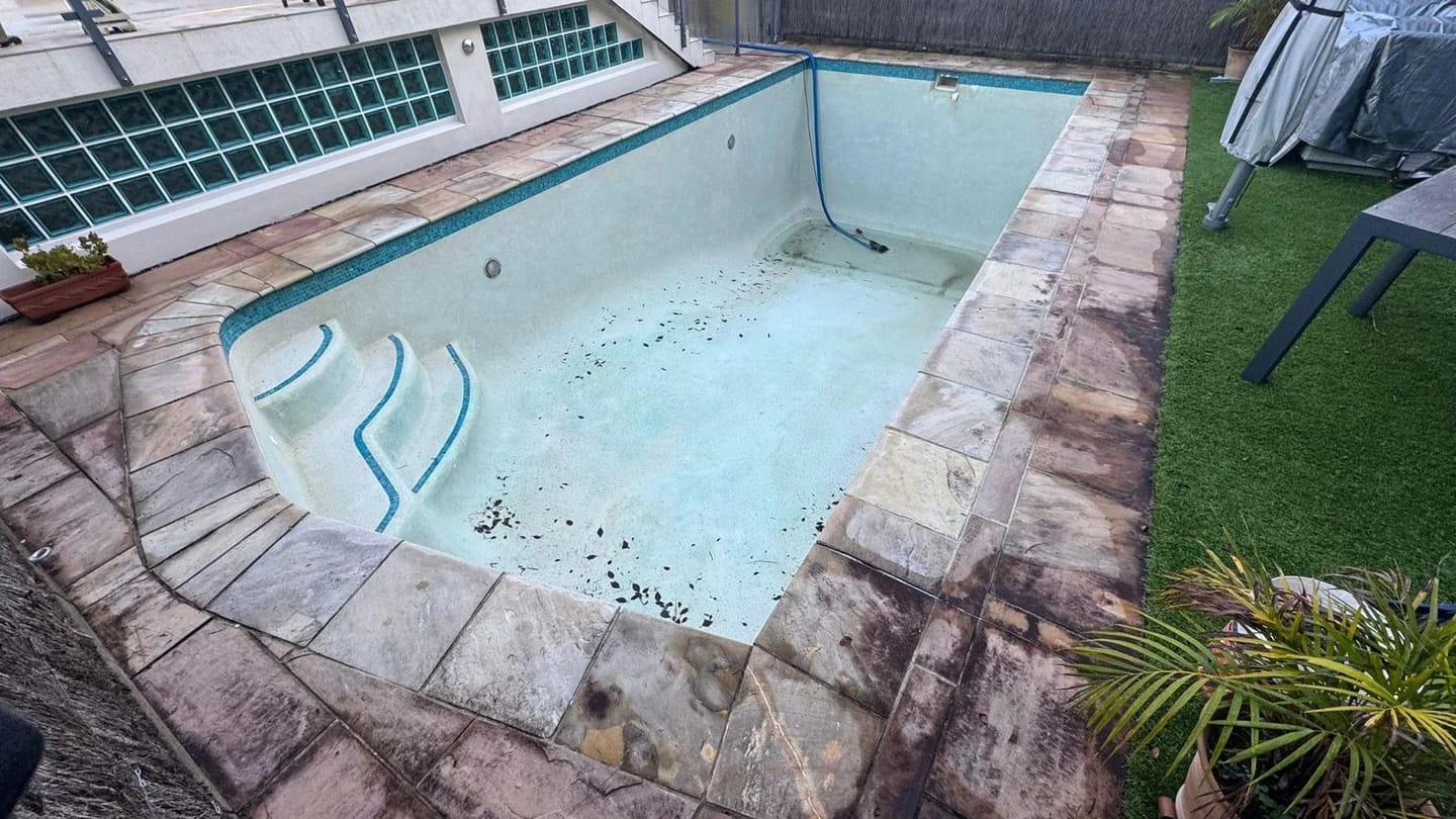 Drained blue residential pool before its interior finish was removed