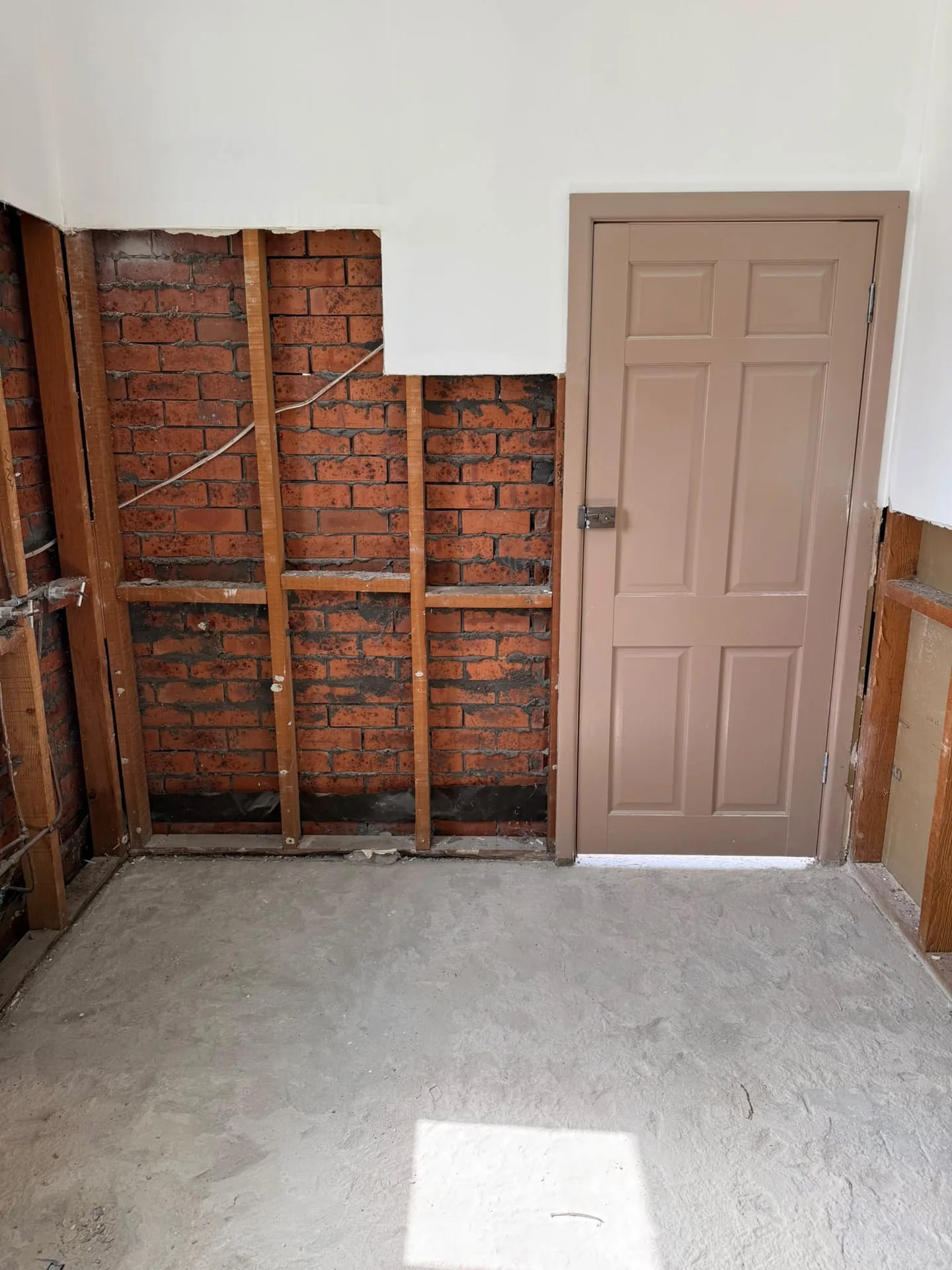 Ryde bathroom after wall and floor tile removal, with masonry and timber framing exposed