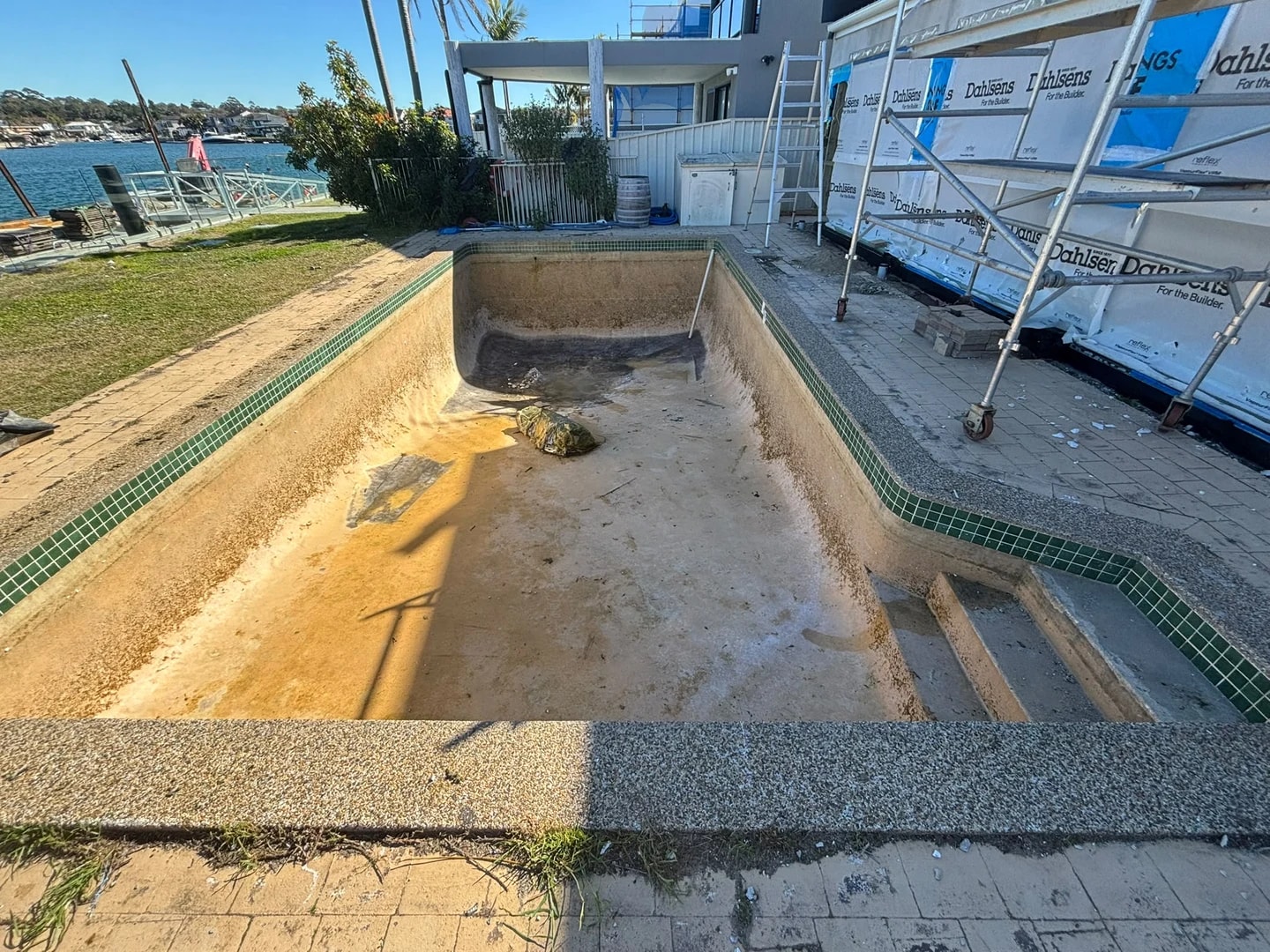 Waterside residential pool during surface removal with the green waterline tiles still visible